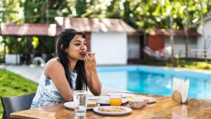 a woman sitting at a table eating food at Hatti Eden Coorg in Gonikoppal