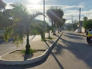 a street with palm trees and a person riding a bike at Casa temporada Araçoiaba in Araçoiaba