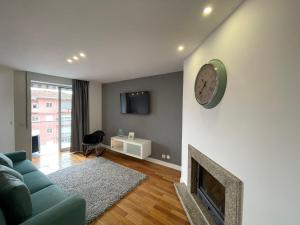 a living room with a couch and a clock on a wall at Apartments City Center • Collection by Perpetual Relax in Braga