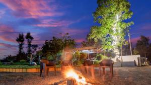 een groep stoelen rond een vuur in een tuin bij Hatti Eden Coorg in Gonikoppal