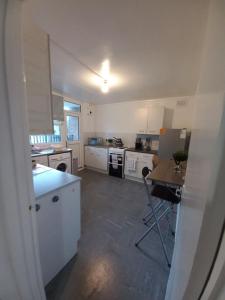 a kitchen with white cabinets and a table in it at Derby City Apartment with free parking in Derby