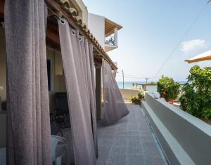 Sunsea Wellness Resort في آغيوس ستيفانوس: شرفة مع ستائر على جانب المنزل