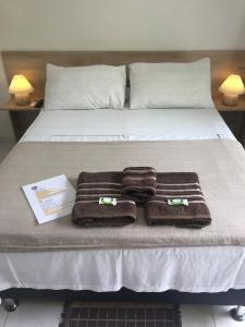 a bed with three towels and a book on it at AYRE GOSTOSO POUSADA in São Miguel do Gostoso
