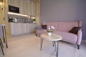 a living room with a pink couch and a table at Apartamenty Bryza-Baltycki - Apartamenty przy plaży z parkingiem in Świnoujście