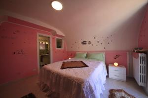 1 dormitorio con 1 cama con paredes rosas y mariposas en la pared en Dolls House, en Minori