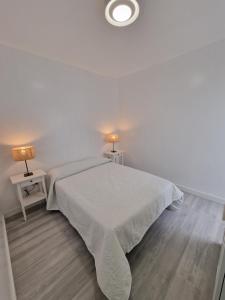 a white bedroom with a white bed and two lamps at GUANARTEME 33 in Las Palmas de Gran Canaria