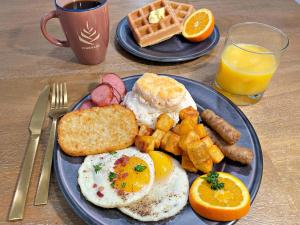 un plato azul de desayuno con huevos, salchichas y gofres en PINEMARK Inn Suites Events, en Saint Clair