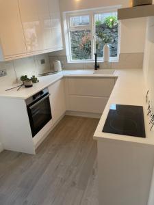 a kitchen with white cabinets and a black stove top oven at Lux Cottage Conwy in Conwy