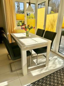 einen weißen Esstisch mit Stühlen und eine Vase aus Blumen in der Unterkunft FeWo Michaela Köst in Konstanz