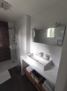 y baño blanco con lavabo y ducha. en L'Ansolanette - Chambre d'hôtes en Fuveau