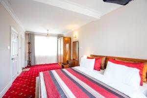 a bedroom with a large bed with a red carpet at Willows Cottage - Little England Cottages in Nuwara Eliya