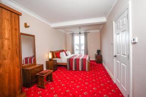 a hotel room with a bed and a red carpet at Willows Cottage - Little England Cottages in Nuwara Eliya