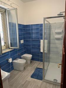 y baño de azulejos azules con aseo y ducha. en Ventura CasaVacanze, en Oliveri