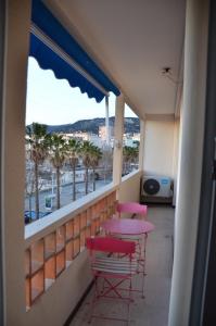 a balcony with pink tables and chairs and a view of the ocean at Portman cosy in Toulon