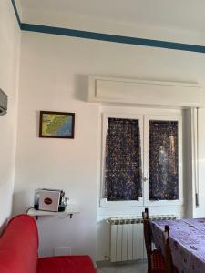 un soggiorno con divano rosso e 2 finestre di Appartamento Marina a Finale Ligure
