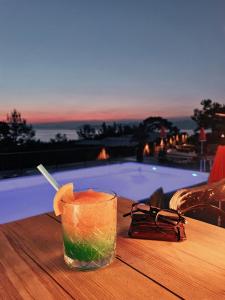 una bebida en una mesa junto a la piscina en Rocas Roja Beach Hotel Faralya, en Faralya