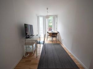 ein Wohnzimmer mit einem Schreibtisch und einem Tisch mit einem TV in der Unterkunft Simple & cosy flat -2 minutes to Nuuks Plads metro in Kopenhagen