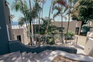 a view from the balcony of a house with palm trees at Ocean Rocks Villa, Umhlanga in Durban