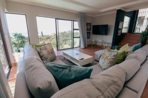 ein Wohnzimmer mit einer großen weißen Couch mit grünen Kissen in der Unterkunft Ocean Rocks Villa, Umhlanga in Durban