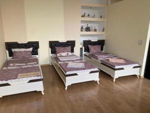three beds in a room with wooden floors at Beaming_House in Sheki
