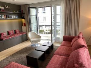 uma sala de estar com um sofá vermelho e uma cadeira em Edward Hopper Suite, Duinhof 3-9-7, spacious apartment near the beach with sunny balcony em Cadzand