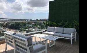 einen Balkon mit einem Sofa, einem Tisch und Stühlen in der Unterkunft Luxury 2 Bedroom Apartment with Huge Balcony , Pool, Gym at Tribute House in Accra