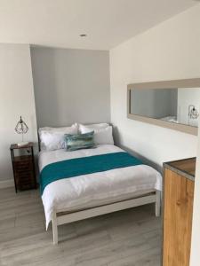 a white bedroom with a bed with a mirror at Luxury Mumbles View Studio Apartment in Swansea