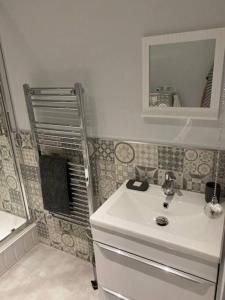 a bathroom with a white sink and a mirror at Luxury Mumbles View Studio Apartment in Swansea