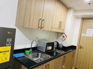 a kitchen with a sink and a microwave at SHORE RESIDENCE D13 shortwalk Mall of asia near airport in Manila