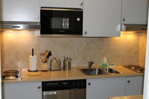 a kitchen counter with a sink and a microwave at Guesthouse - Kuin Kotonaan in Kotka