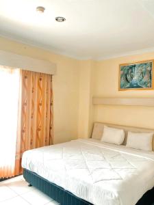 1 dormitorio con 1 cama blanca y ventana en Permata Inn Slawi, en Procot