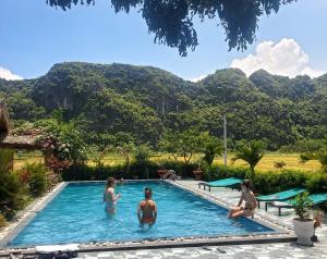 um grupo de mulheres numa piscina com montanhas ao fundo em Tam Coc Minh Hung Homestay em Ninh Binh