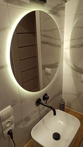 ein Badezimmer mit einem weißen Waschbecken und einem Spiegel in der Unterkunft Underground Apartament in Łomża
