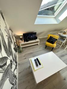 L'ENSOLEILLÉ - Classé 2 étoiles - Nay centre - Appartement في Nay: غرفة معيشة مع طاولة بيضاء وكرسي اصفر