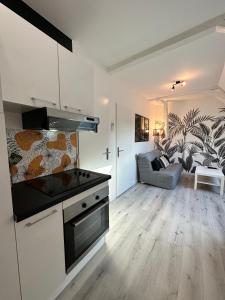 a kitchen with a stove top oven next to a living room at L'ENSOLEILLÉ - Classé 2 étoiles - Nay centre - Appartement in Nay