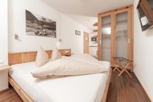 a bedroom with a white bed and a television at Aparthotel Ambiente in Umhausen