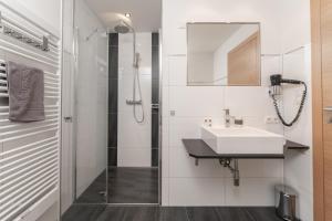 a white bathroom with a sink and a mirror at Aparthotel Ambiente in Umhausen