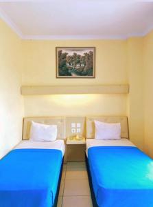 2 camas en una habitación de color azul y blanco en Permata Inn Slawi, en Procot