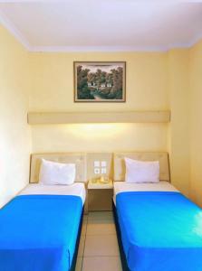 two beds in a room with blue and white at Permata Inn Slawi in Procot