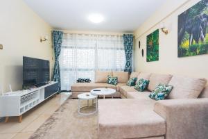 a living room with a couch and a tv at Tropical themed 3BR and DSQ Apartment in Nairobi