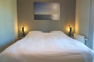 1 dormitorio con 1 cama blanca grande con una foto en la pared en Caramia, Duinhof 5-1-14, Romantic apartment by the sea en Cadzand-Bad