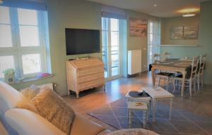 ein Wohnzimmer mit einem Sofa, einem Tisch und einem TV in der Unterkunft Caramia, Duinhof 5-1-14, Romantic apartment by the sea in Cadzand-Bad