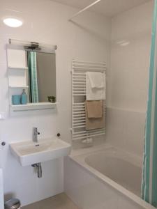 a white bathroom with a sink and a bath tub at Vienna Belvedere und Hauptbahnhof Apartment in Vienna