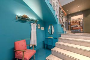 Habitación azul con escaleras y silla roja en Kimon Hotel Athens, en Atenas