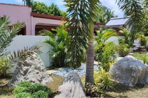 a garden with a palm tree and rocks at Casa LeoMa in Cavite