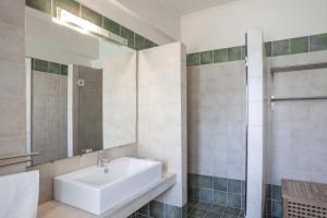 La salle de bains blanche est pourvue d'un lavabo et d'une douche. dans l'établissement Kassiopi Seafront Elegant Apartments, à Kassiopi