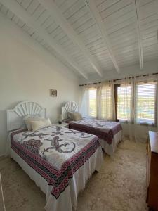 1 Schlafzimmer mit 2 Betten und 2 Fenstern in der Unterkunft Río Mar Cumayasa in La Romana