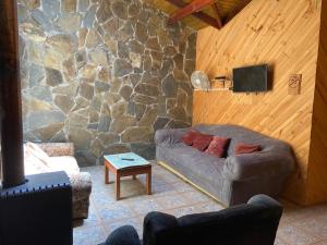 a living room with a couch and a stone wall at Camping y Cabañas Playa Caliboro in Los Ángeles
