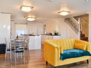 a living room with a yellow couch and a kitchen at Ailsa Craig View in Stranraer