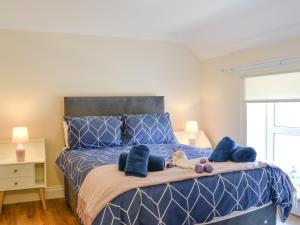 a bedroom with a blue bed with stuffed animals on it at Ailsa Craig View in Stranraer
